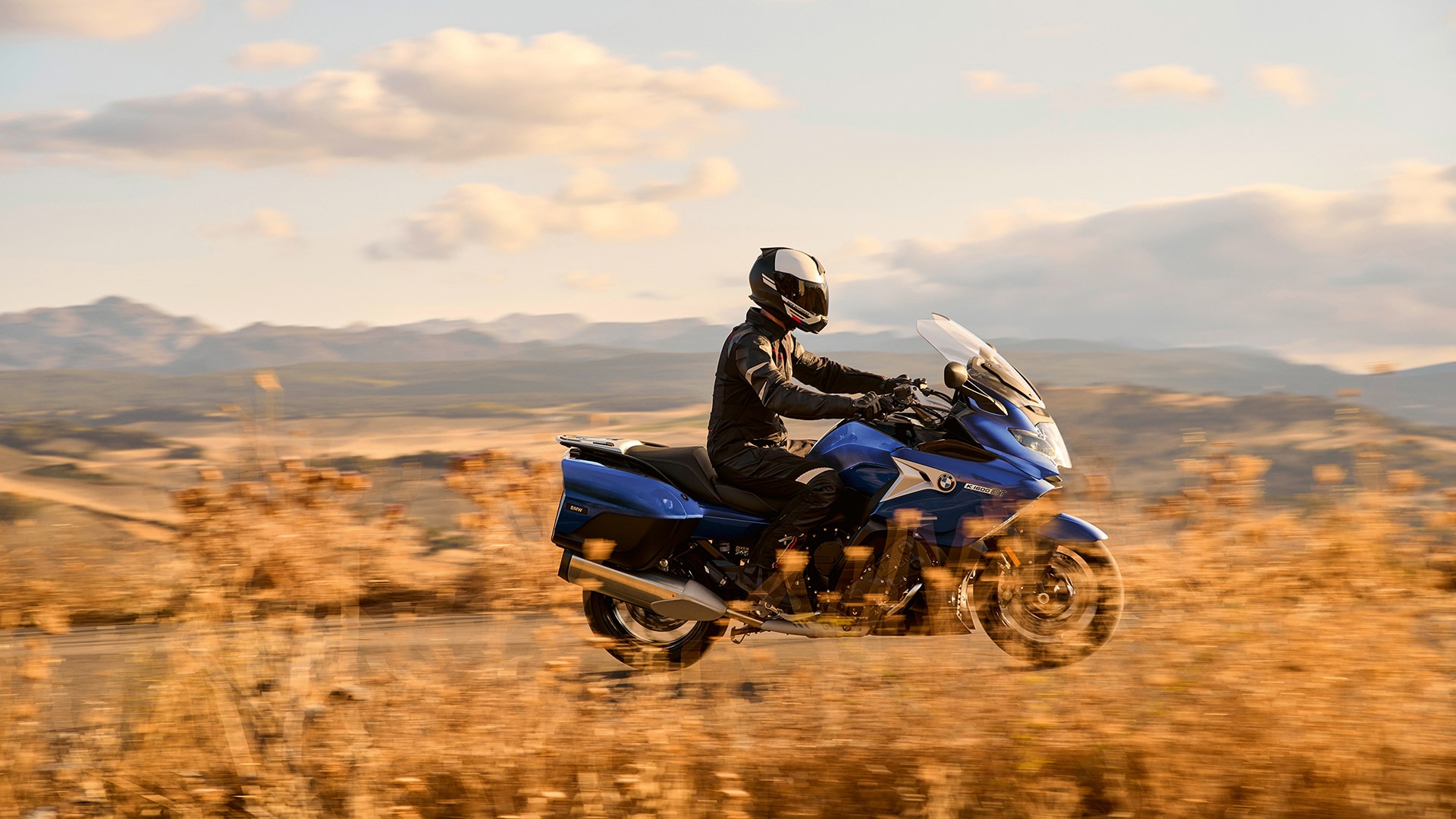 K 1600 GT в Style Sport пътува на фона хълмиста местност със сухи треви.
