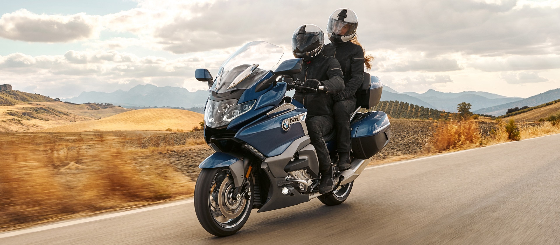K 1600 GTL в Gravity Blue със спътник, движещ се на фона на хълмиста местност.